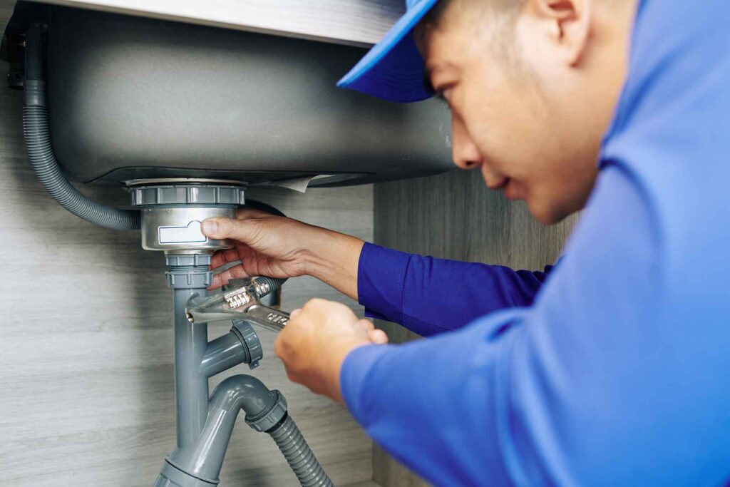 plumber-repairing-a-leaky-drain-ETFEBHP.jpg